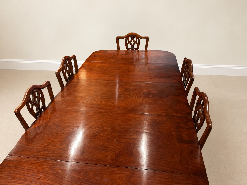 An extendable Regency mahogany dining table featuring rounded D-shaped ends, extra leaf insertions, and turned legs with brass castors. View VI