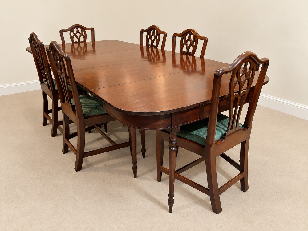 An extendable Regency mahogany dining table featuring rounded D-shaped ends, extra leaf insertions, and turned legs with brass castors. View VII
