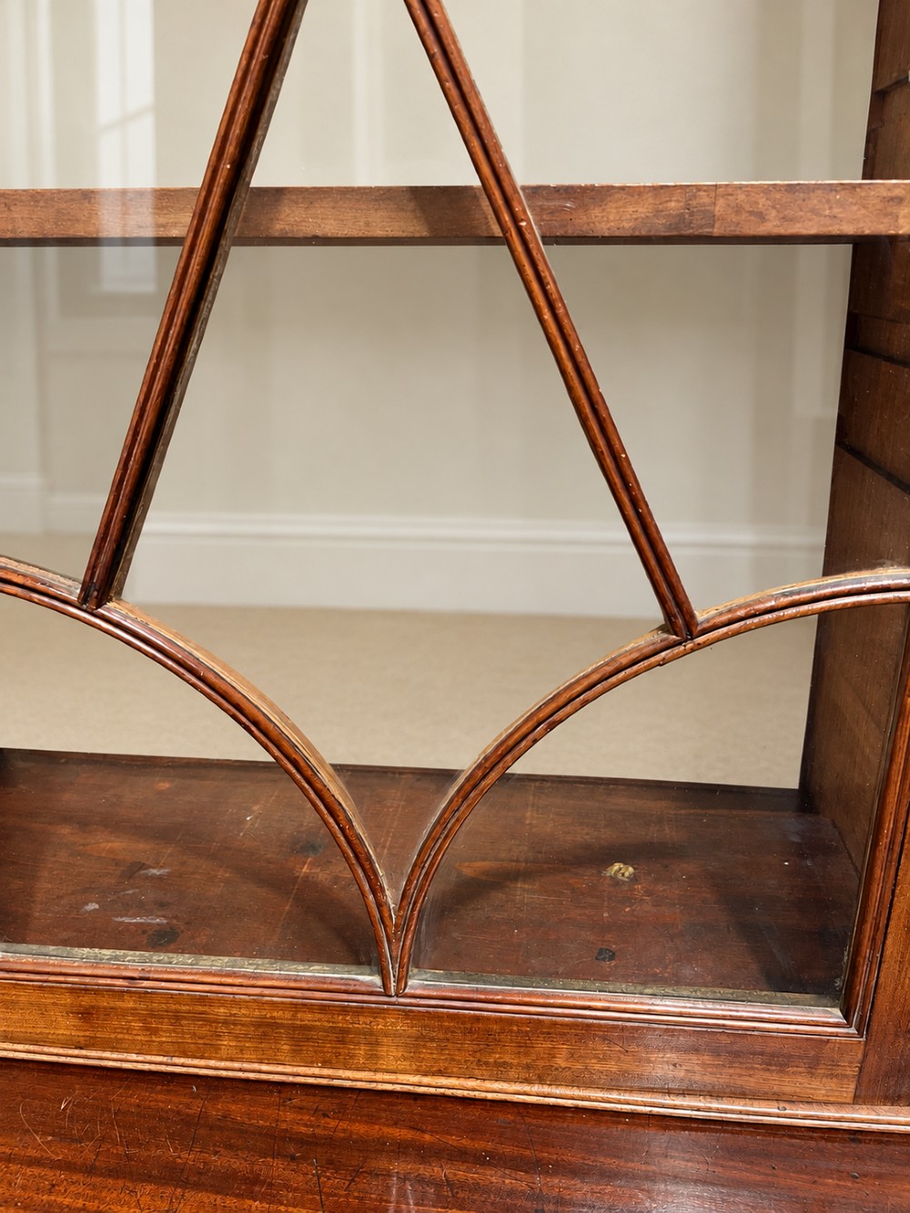 A 19th-century mahogany secretaire bookcase featuring an arched pediment, astragal glazed upper doors, and a four-drawer base with circular brass handles. View IV