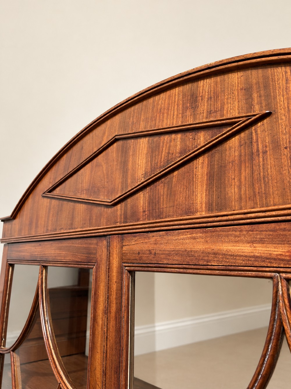 A 19th-century mahogany secretaire bookcase featuring an arched pediment, astragal glazed upper doors, and a four-drawer base with circular brass handles. View VI