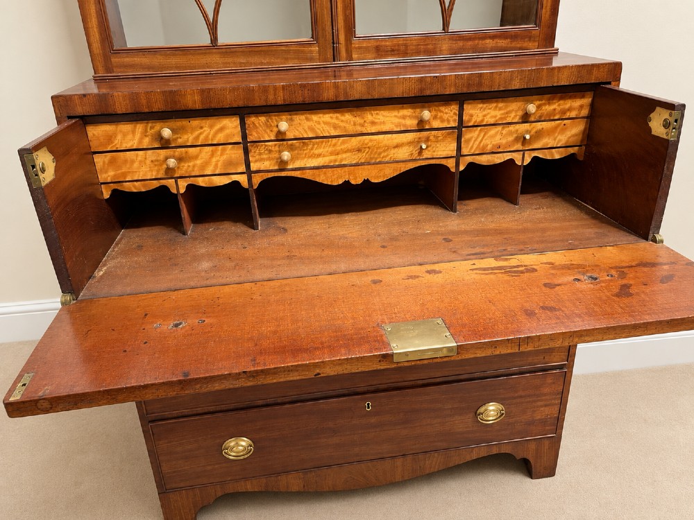 A 19th-century mahogany secretaire bookcase featuring an arched pediment, astragal glazed upper doors, and a four-drawer base with circular brass handles. View VII