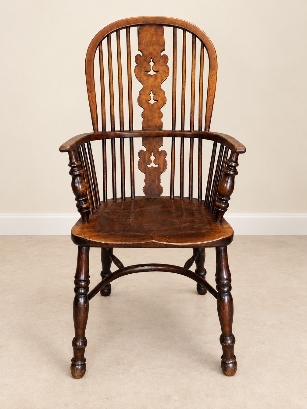 An antique 19th-century wooden Windsor armchair featuring a hoop back with turned spindles, a central pierced splat, a contoured saddle seat, and curved armrests supported by turned front legs. View II