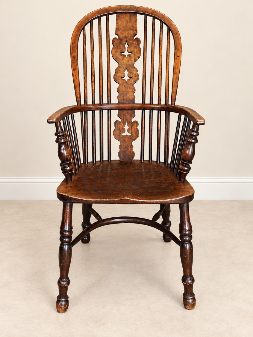 An antique 19th-century wooden Windsor armchair featuring a hoop back with turned spindles, a central pierced splat, a contoured saddle seat, and curved armrests supported by turned front legs. View III