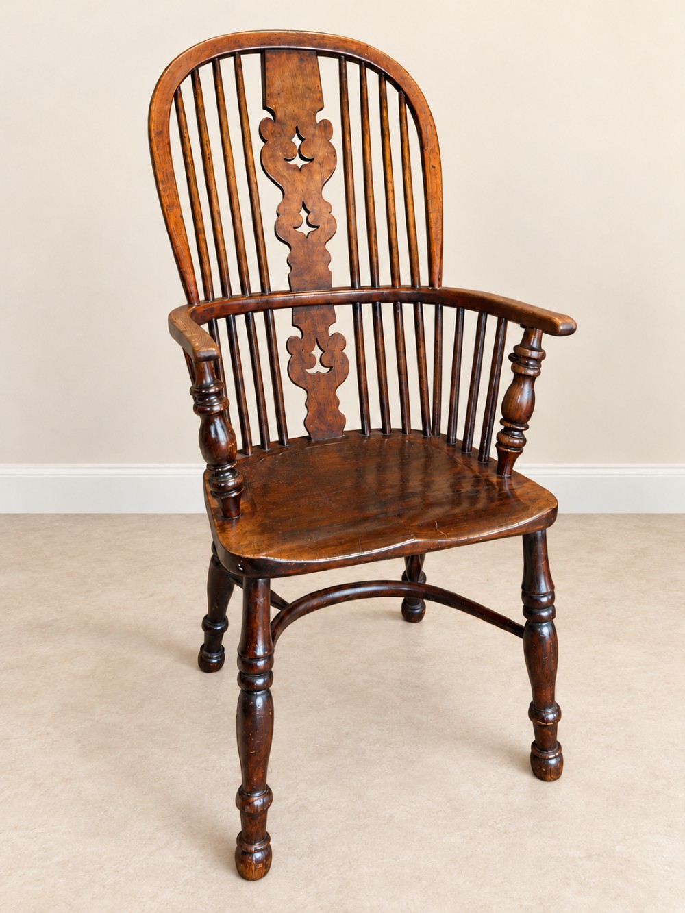 An antique 19th-century wooden Windsor armchair featuring a hoop back with turned spindles, a central pierced splat, a contoured saddle seat, and curved armrests supported by turned front legs. View IV