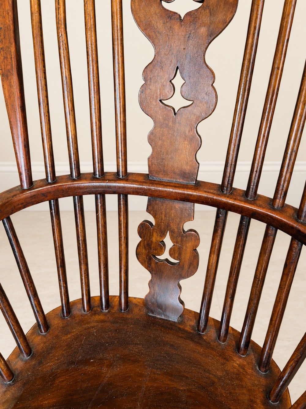 An antique 19th-century wooden Windsor armchair featuring a hoop back with turned spindles, a central pierced splat, a contoured saddle seat, and curved armrests supported by turned front legs. View VI