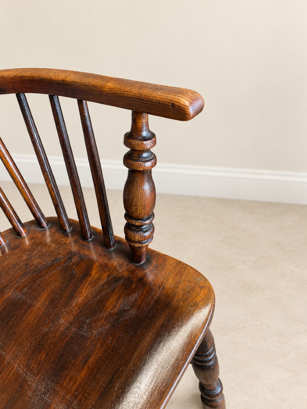 An antique 19th-century wooden Windsor armchair featuring a hoop back with turned spindles, a central pierced splat, a contoured saddle seat, and curved armrests supported by turned front legs. View VII