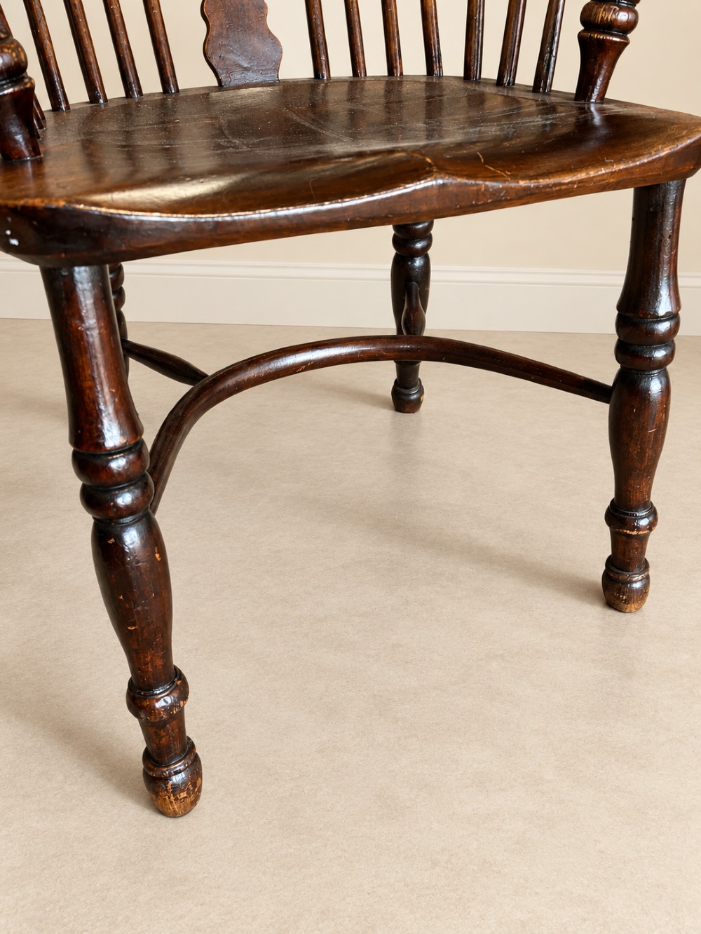 An antique 19th-century wooden Windsor armchair featuring a hoop back with turned spindles, a central pierced splat, a contoured saddle seat, and curved armrests supported by turned front legs. View VIII