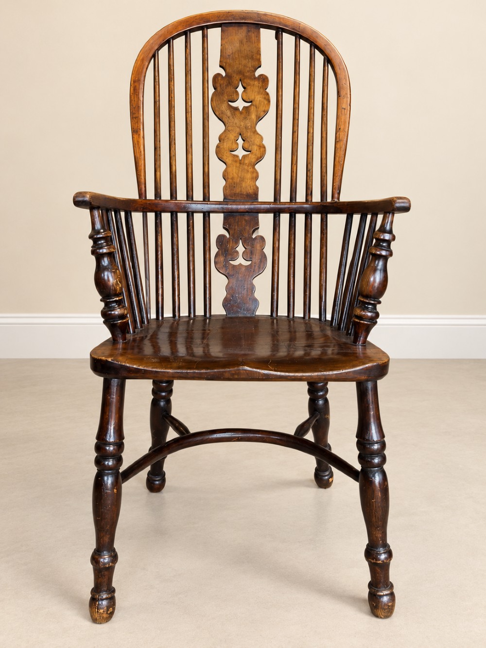 An antique 19th-century wooden Windsor armchair featuring a hoop back with turned spindles, a central pierced splat, a contoured saddle seat, and curved armrests supported by turned front legs. View IX