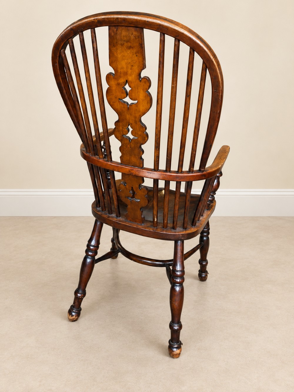 An antique 19th-century wooden Windsor armchair featuring a hoop back with turned spindles, a central pierced splat, a contoured saddle seat, and curved armrests supported by turned front legs. View XI