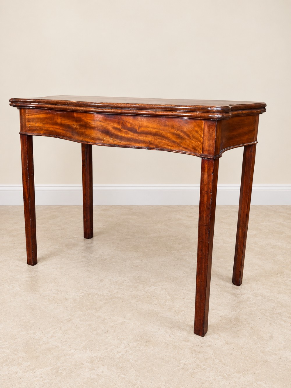 An antique Georgian dark mahogany fold-over table featuring a serpentine-curved front apron and four straight legs. View II