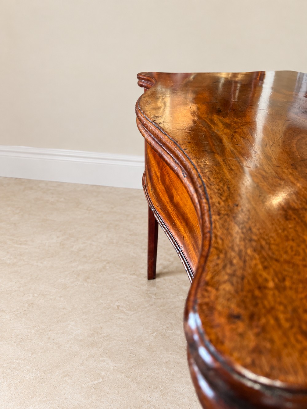 An antique Georgian dark mahogany fold-over table featuring a serpentine-curved front apron and four straight legs. View VII