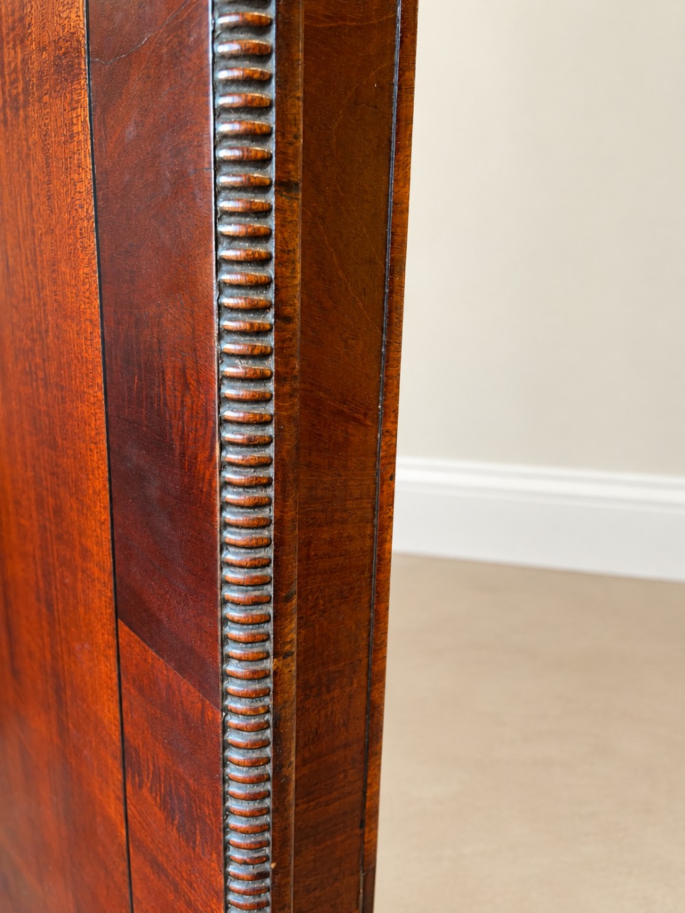 A Regency period mahogany dining table featuring a square top with rounded corners, supported by a central pedestal and four splayed legs with brass castors. View X