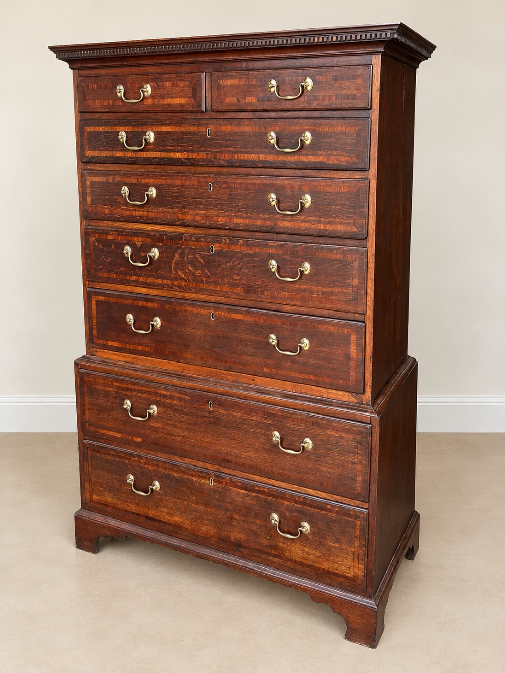 An antique Georgian oak chest on chest featuring two small top drawers over five full-width graduated drawers with brass swan-neck handles and bracket feet. View V