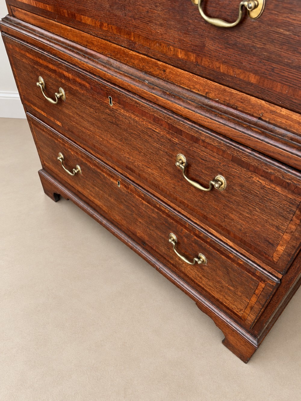 An antique Georgian oak chest on chest featuring two small top drawers over five full-width graduated drawers with brass swan-neck handles and bracket feet. View VIII