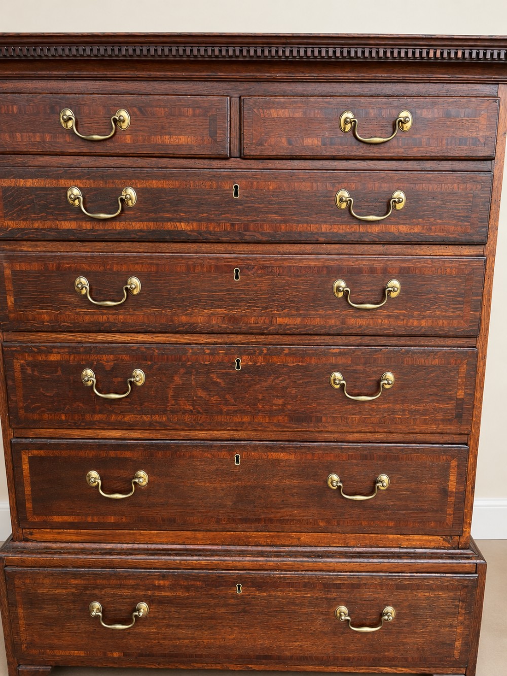 An antique Georgian oak chest on chest featuring two small top drawers over five full-width graduated drawers with brass swan-neck handles and bracket feet. View IX