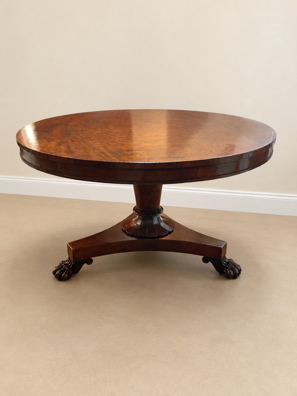 A 19th-century circular mahogany dining table featuring a polished top, turned central column with gadrooned base, and a tri-form platform resting on carved claw feet. View II