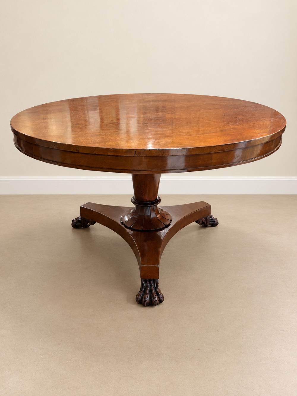 A 19th-century circular mahogany dining table featuring a polished top, turned central column with gadrooned base, and a tri-form platform resting on carved claw feet. View IV