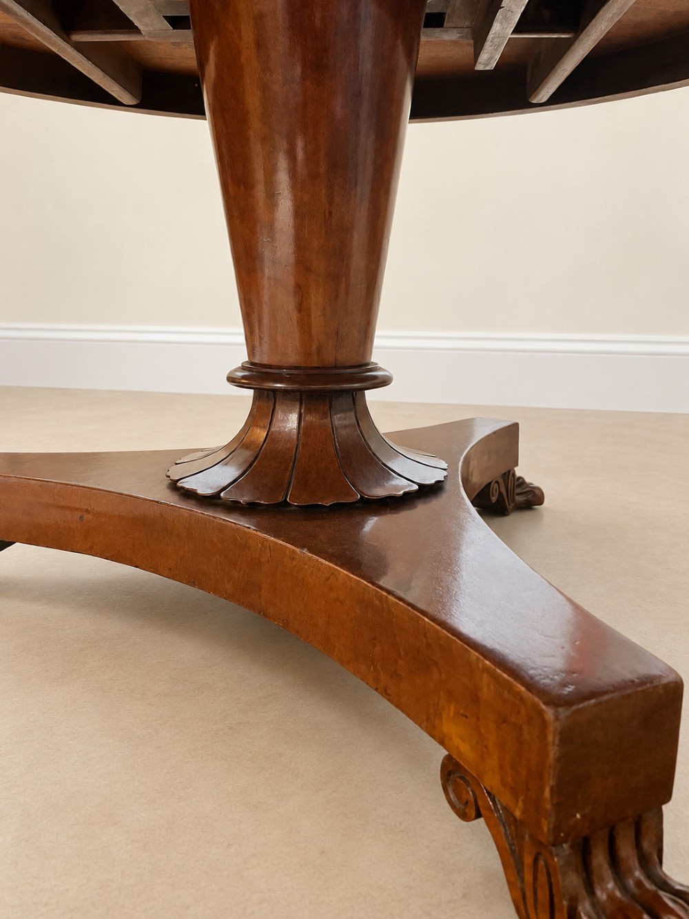 A 19th-century circular mahogany dining table featuring a polished top, turned central column with gadrooned base, and a tri-form platform resting on carved claw feet. View VI