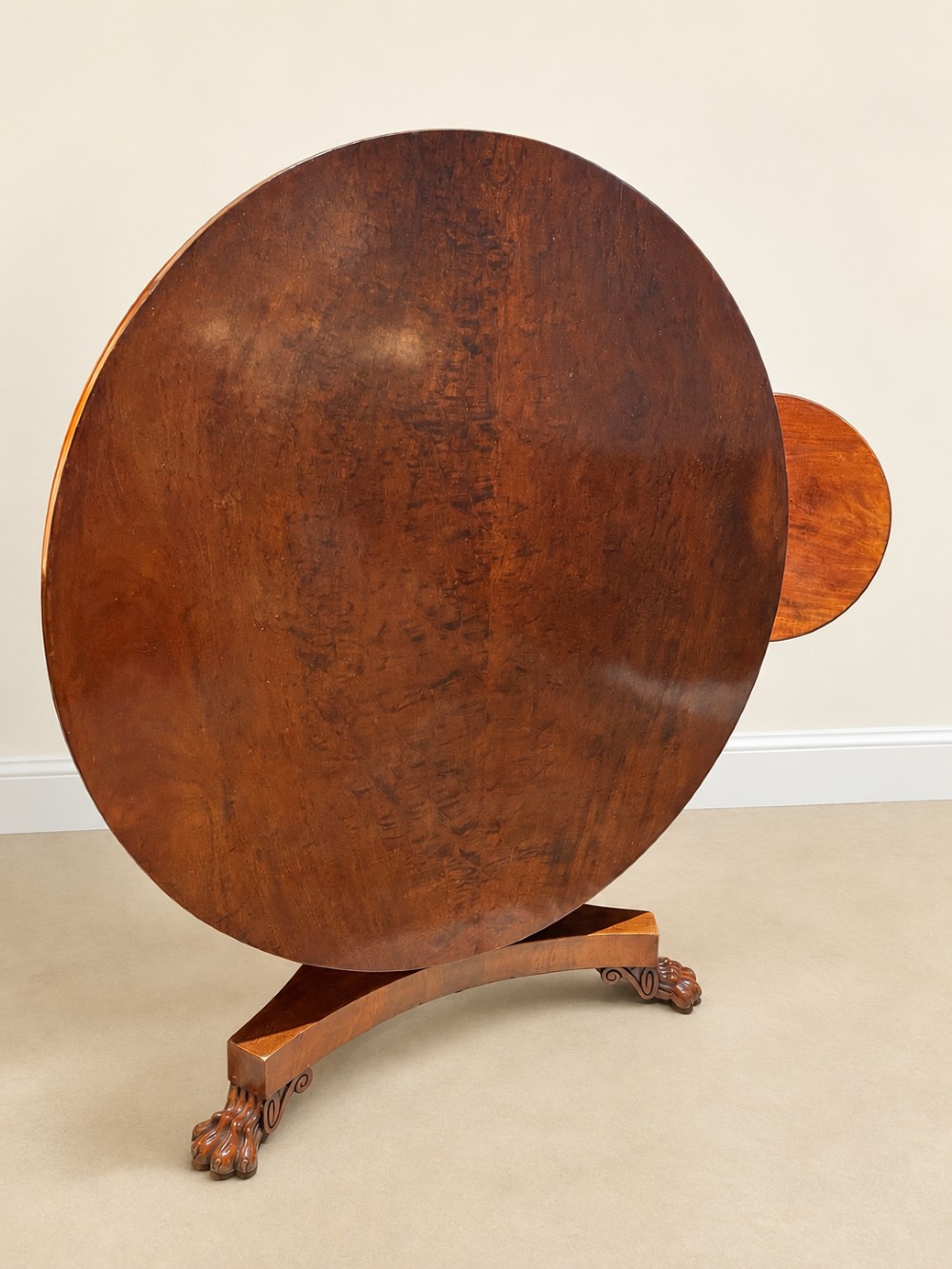 A 19th-century circular mahogany dining table featuring a polished top, turned central column with gadrooned base, and a tri-form platform resting on carved claw feet. View IX