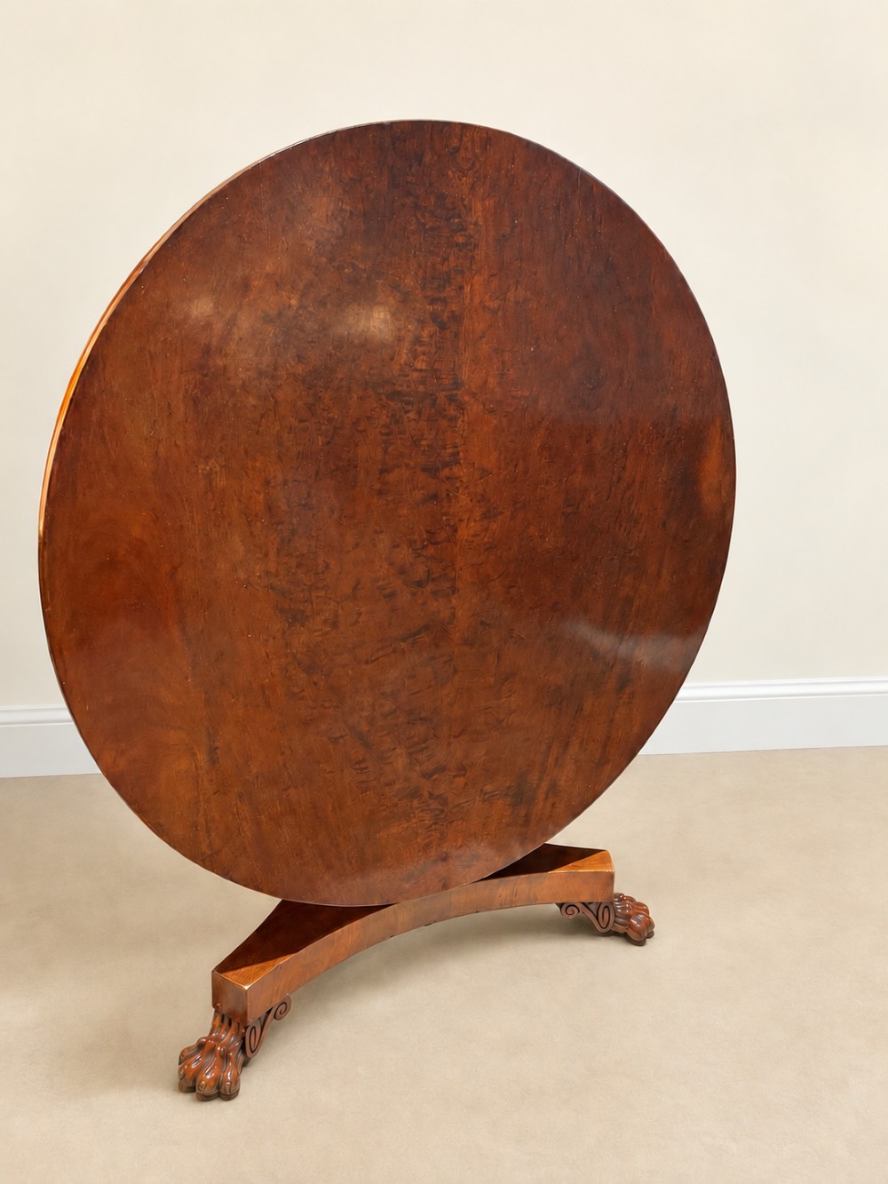 A 19th-century circular mahogany dining table featuring a polished top, turned central column with gadrooned base, and a tri-form platform resting on carved claw feet. View X