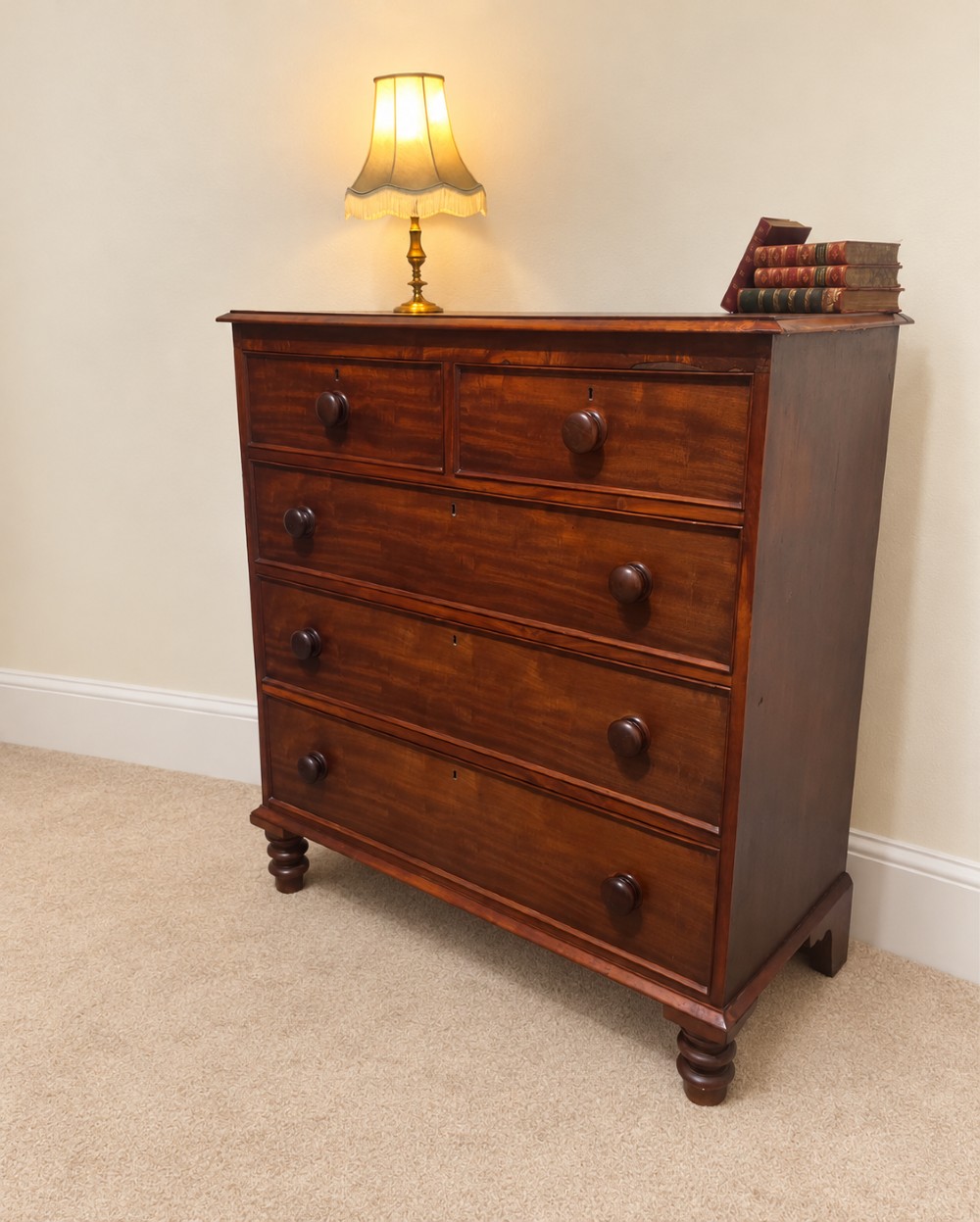 A nineteenth-century mahogany chest of drawers featuring two short over three long drawers with turned wooden knobs and turned feet. View II