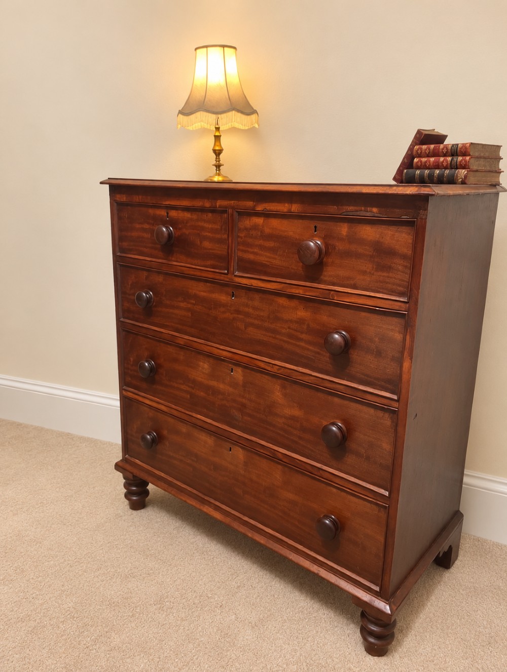 A nineteenth-century mahogany chest of drawers featuring two short over three long drawers with turned wooden knobs and turned feet. View III