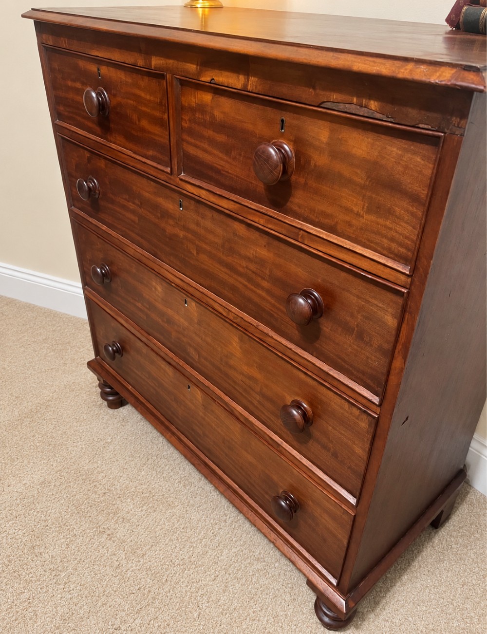 A nineteenth-century mahogany chest of drawers featuring two short over three long drawers with turned wooden knobs and turned feet. View VI