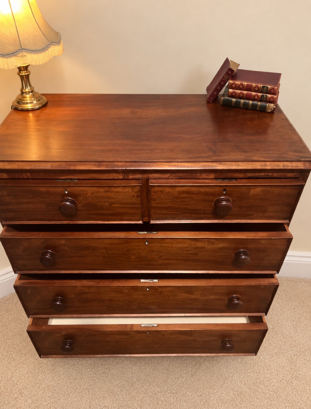 A nineteenth-century mahogany chest of drawers featuring two short over three long drawers with turned wooden knobs and turned feet. View VII