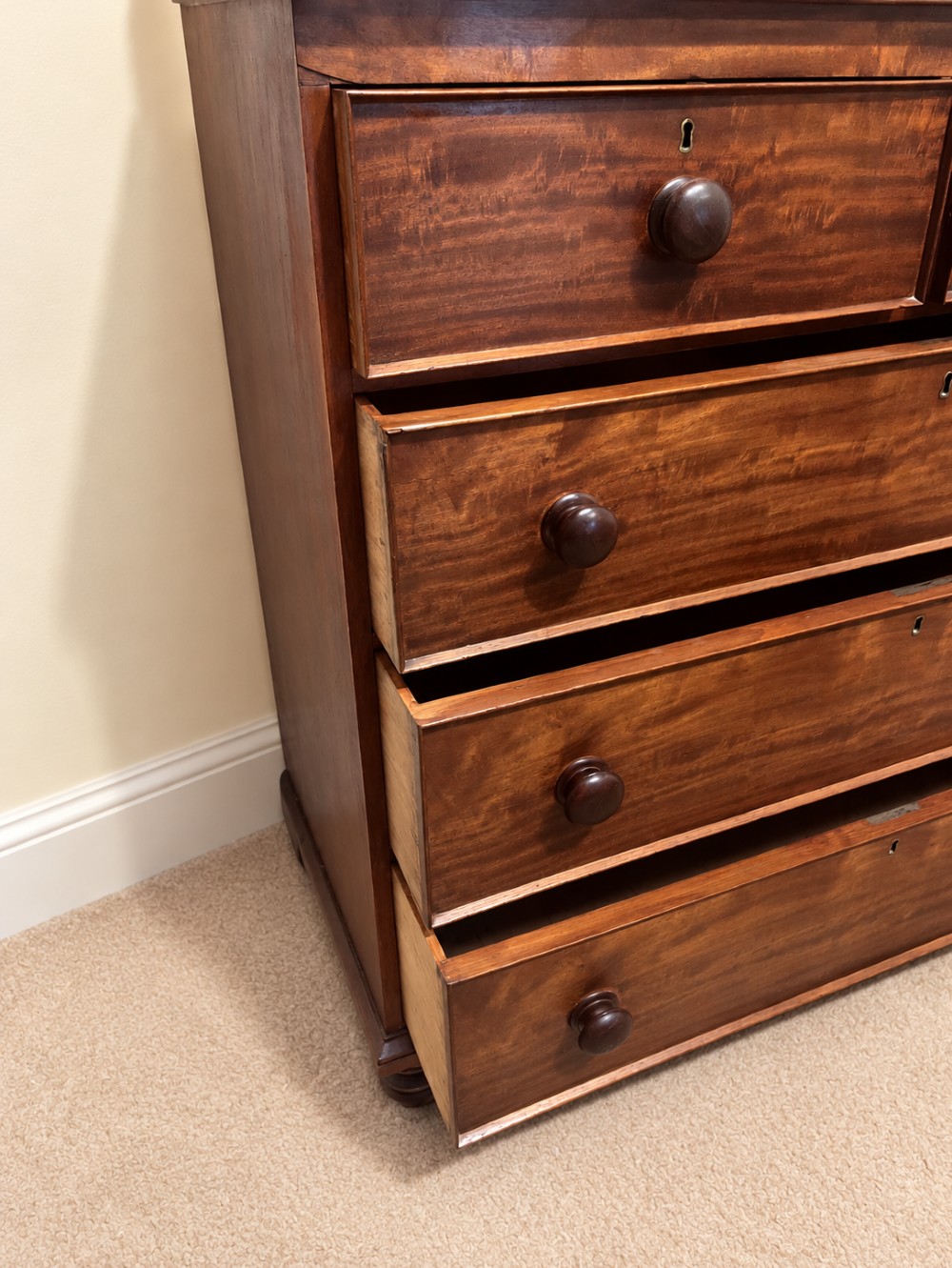 A nineteenth-century mahogany chest of drawers featuring two short over three long drawers with turned wooden knobs and turned feet. View VIII