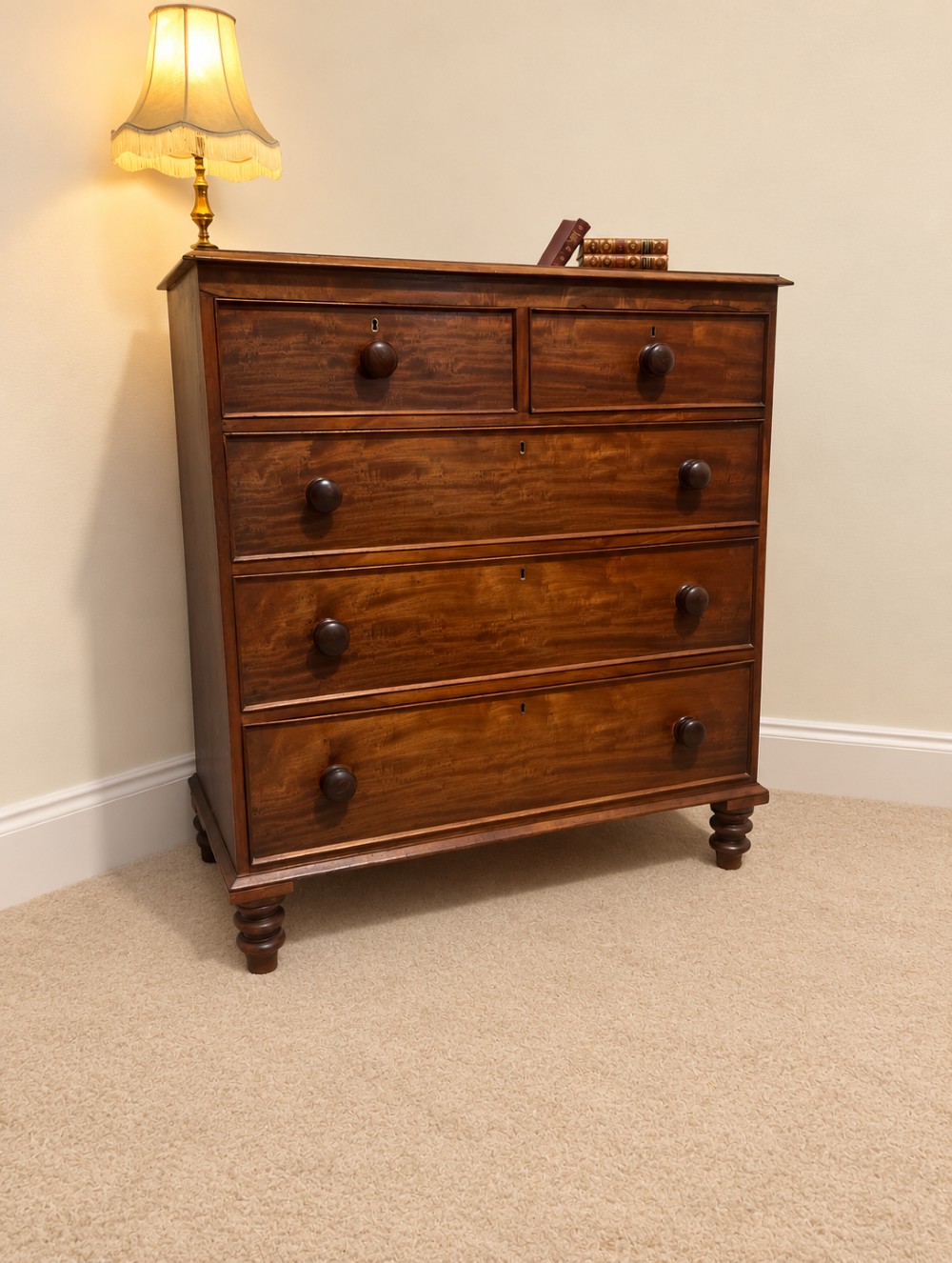 A nineteenth-century mahogany chest of drawers featuring two short over three long drawers with turned wooden knobs and turned feet. View IX
