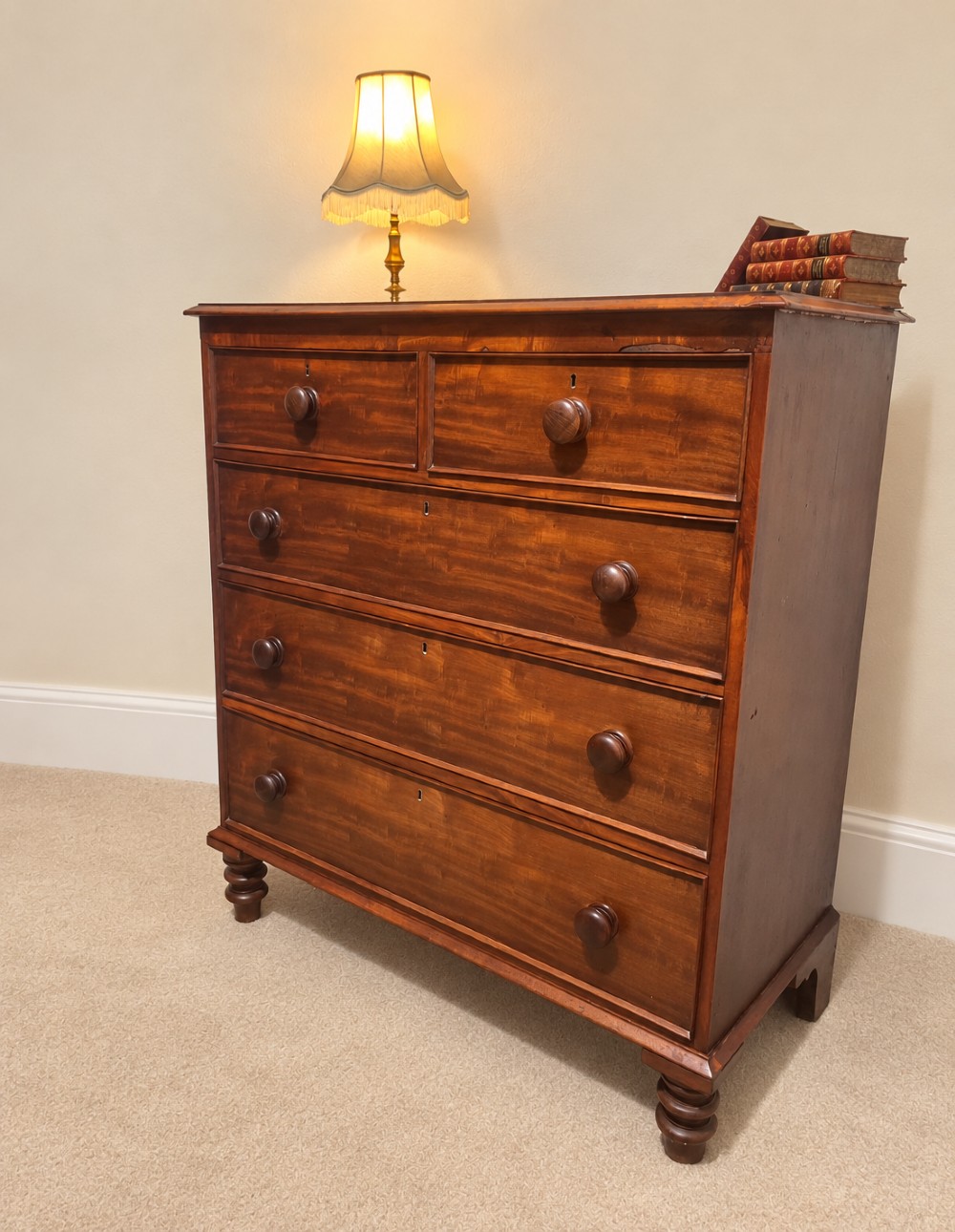 A nineteenth-century mahogany chest of drawers featuring two short over three long drawers with turned wooden knobs and turned feet. View X