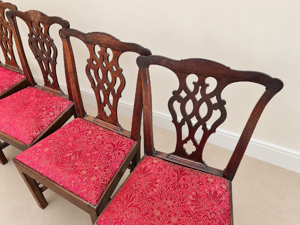 A set of six dark mahogany Georgian dining chairs featuring intricately pierced back splats and red patterned fabric drop-in seats. View II