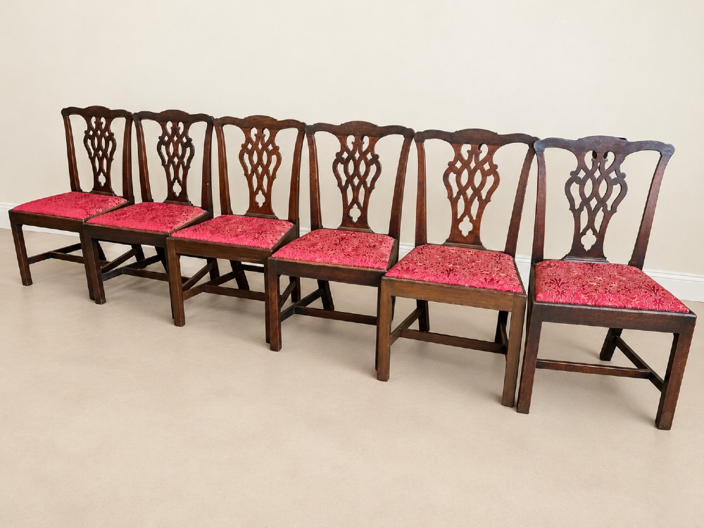 A set of six dark mahogany Georgian dining chairs featuring intricately pierced back splats and red patterned fabric drop-in seats. View III