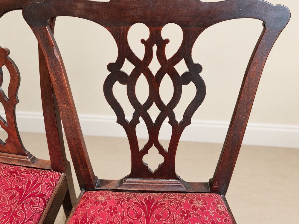 A set of six dark mahogany Georgian dining chairs featuring intricately pierced back splats and red patterned fabric drop-in seats. View V