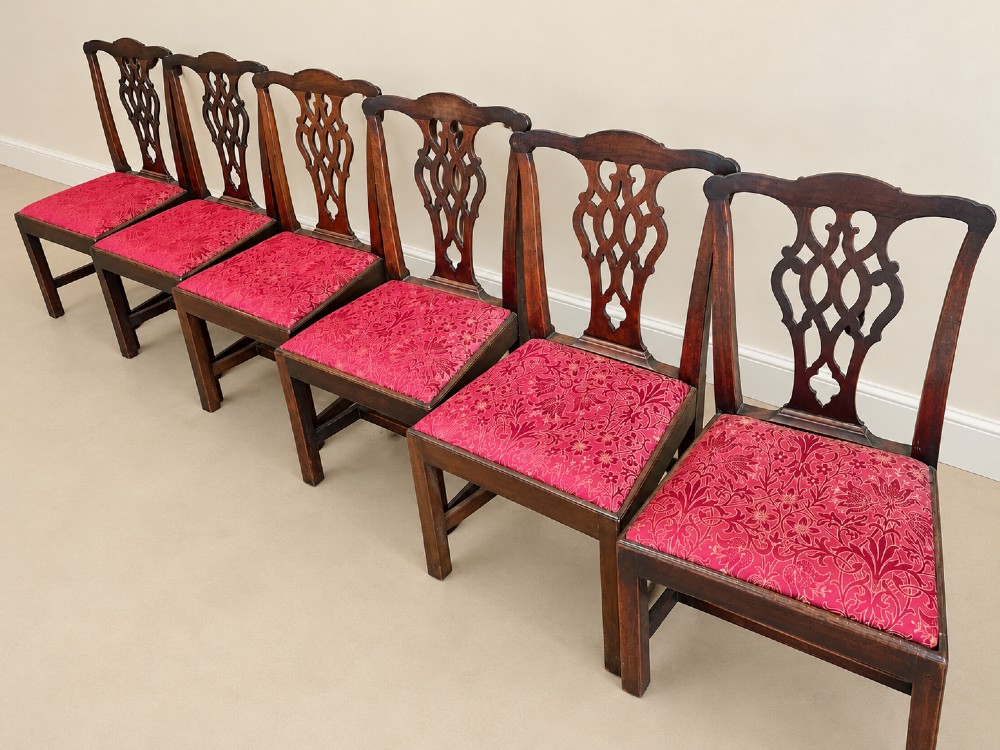 A set of six dark mahogany Georgian dining chairs featuring intricately pierced back splats and red patterned fabric drop-in seats. View VI