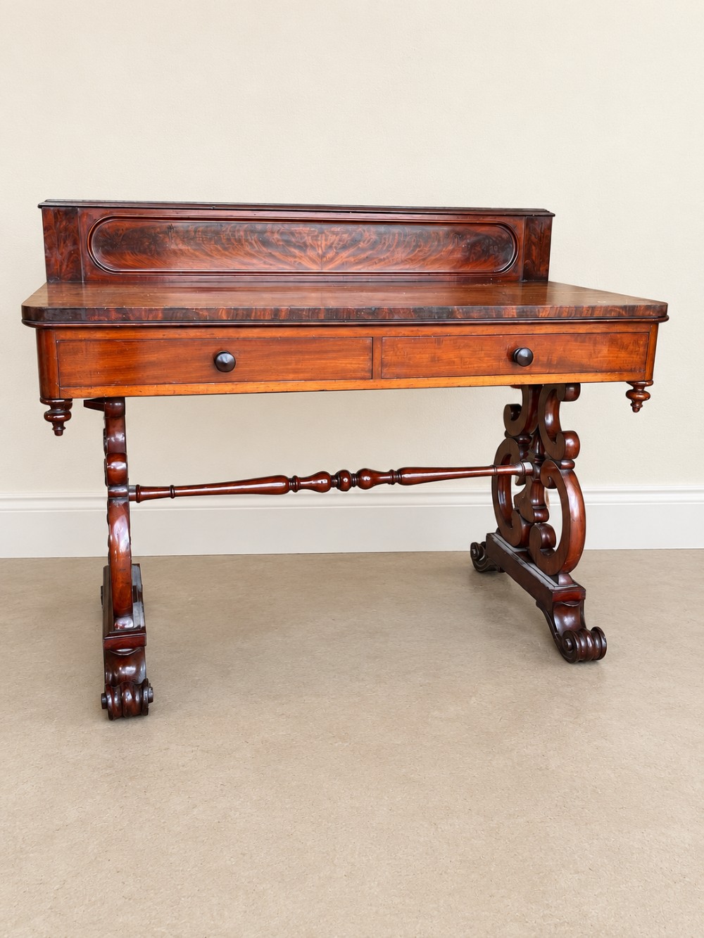 A 19th-century mahogany writing desk with a low gallery back, two frieze drawers, carved scroll trestle legs, and a turned stretcher. View III