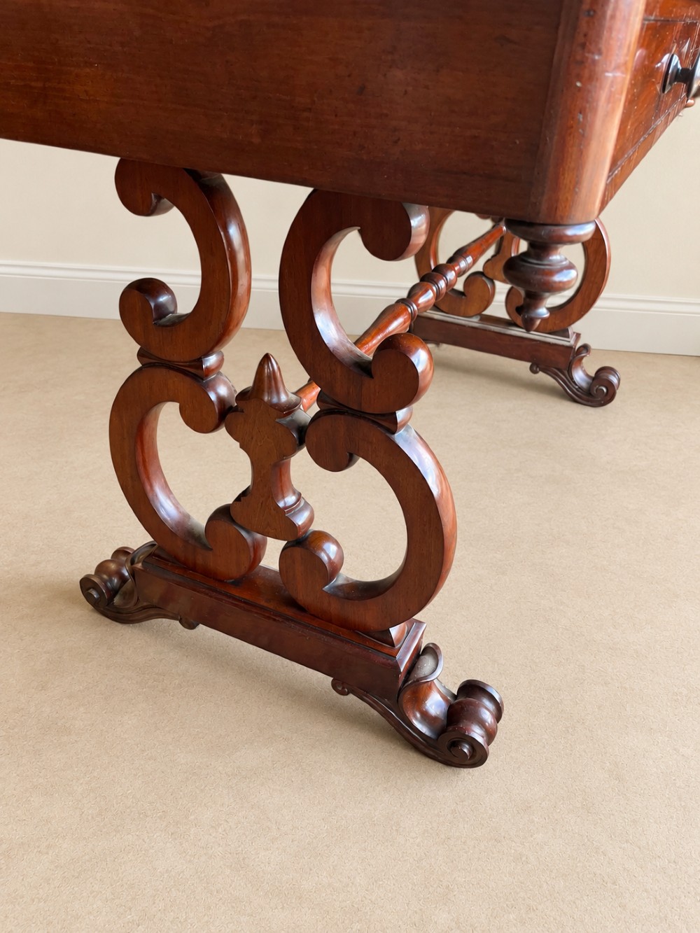 A 19th-century mahogany writing desk with a low gallery back, two frieze drawers, carved scroll trestle legs, and a turned stretcher. View V