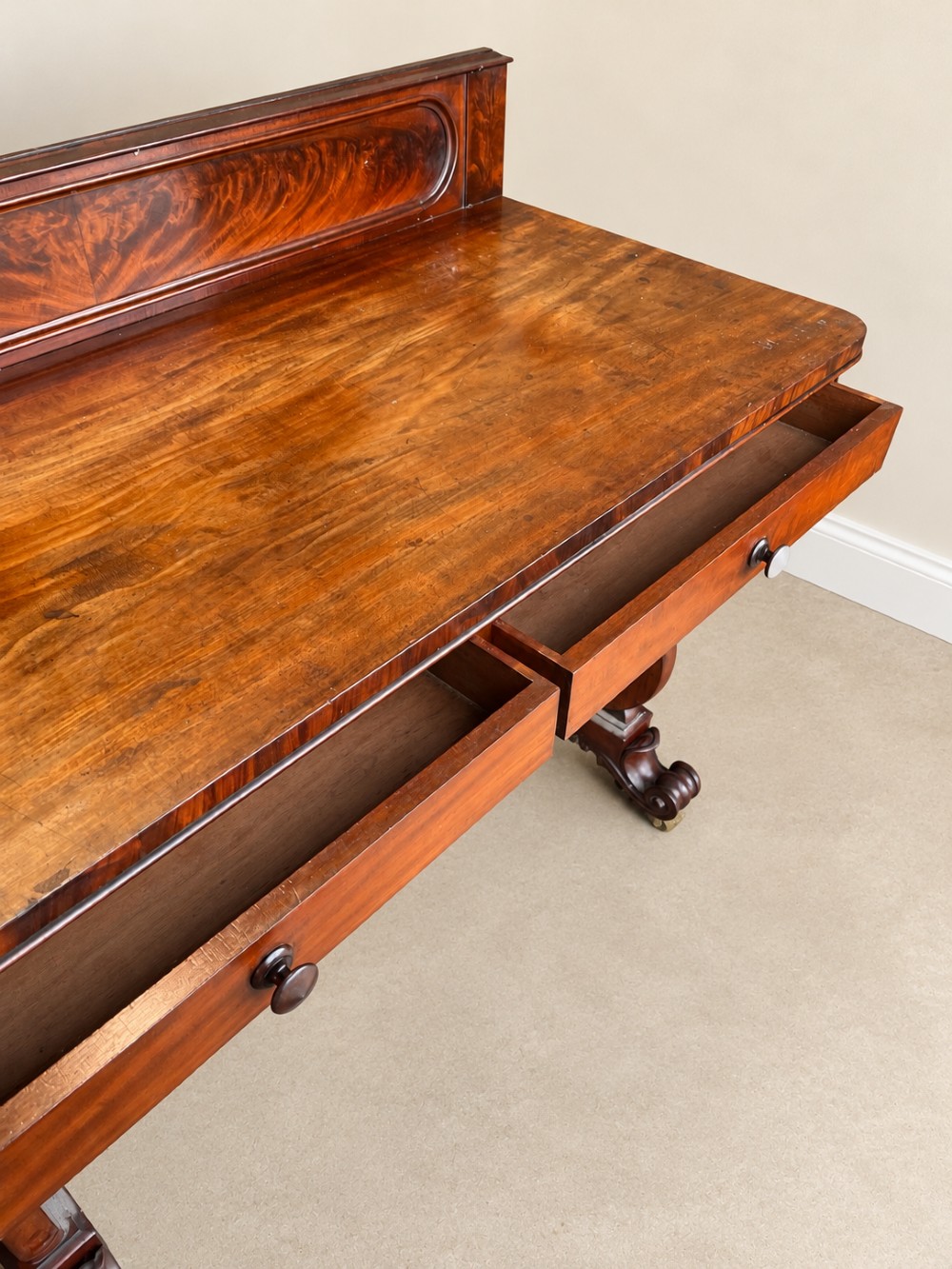 A 19th-century mahogany writing desk with a low gallery back, two frieze drawers, carved scroll trestle legs, and a turned stretcher. View VIII