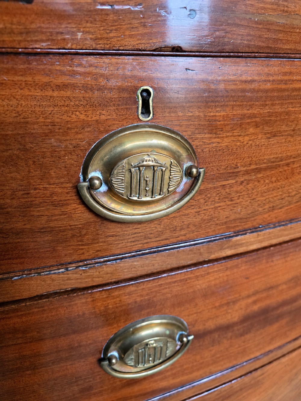 A nineteenth-century mahogany bowfront chest of drawers featuring two short drawers above three long graduated drawers with oval brass handles and splayed bracket feet. View IX