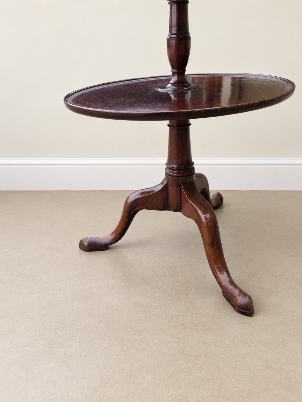 A Georgian mahogany three-tiered dumb waiter with graduated circular trays supported by a turned central pillar on a tripod base. View II
