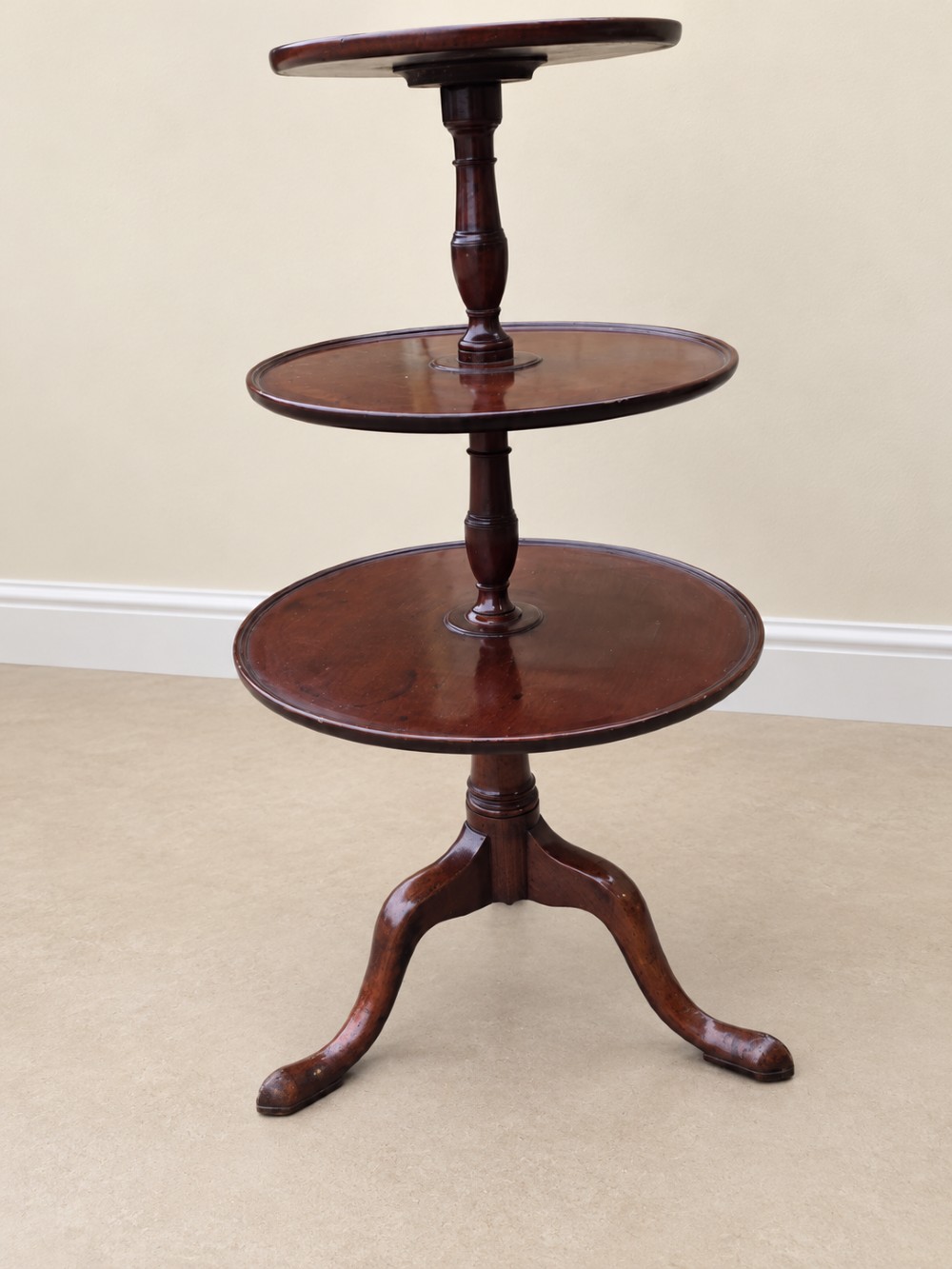 A Georgian mahogany three-tiered dumb waiter with graduated circular trays supported by a turned central pillar on a tripod base. View III