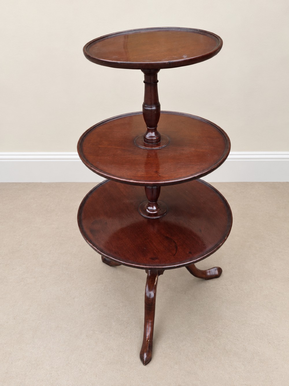 A Georgian mahogany three-tiered dumb waiter with graduated circular trays supported by a turned central pillar on a tripod base. View IV