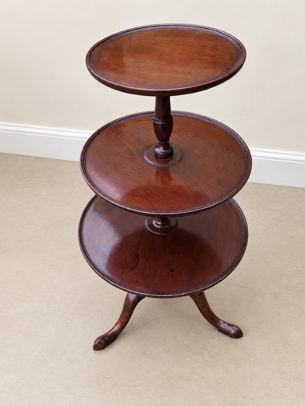 A Georgian mahogany three-tiered dumb waiter with graduated circular trays supported by a turned central pillar on a tripod base. View V