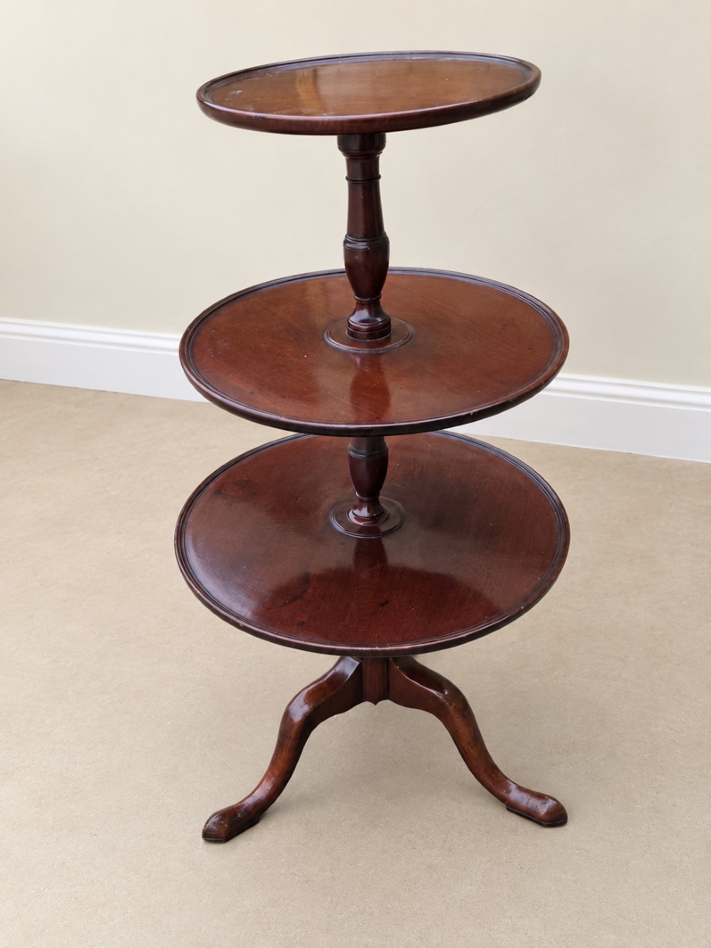 A Georgian mahogany three-tiered dumb waiter with graduated circular trays supported by a turned central pillar on a tripod base. View VI