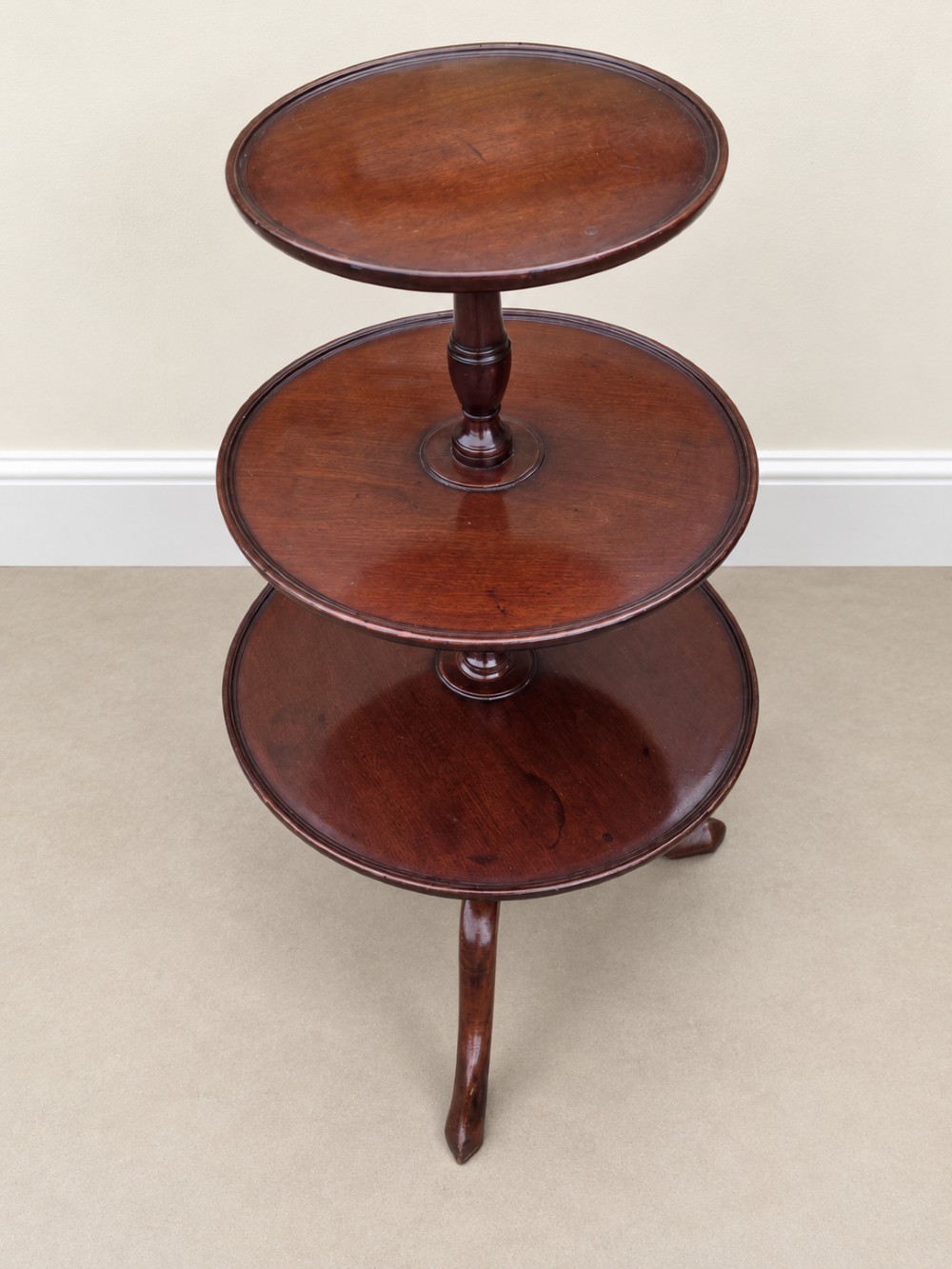 A Georgian mahogany three-tiered dumb waiter with graduated circular trays supported by a turned central pillar on a tripod base. View VII