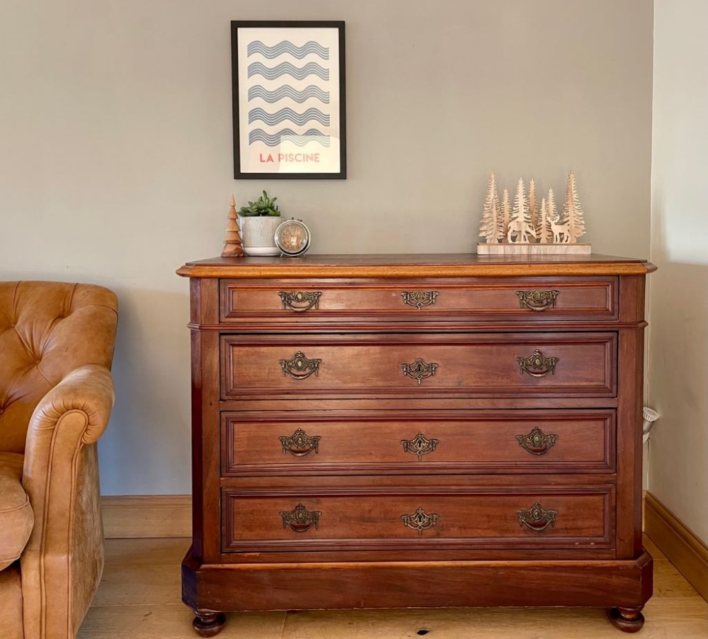 An early twentieth-century French wooden commode chest with four moulded drawers and ornate brass drop handles.