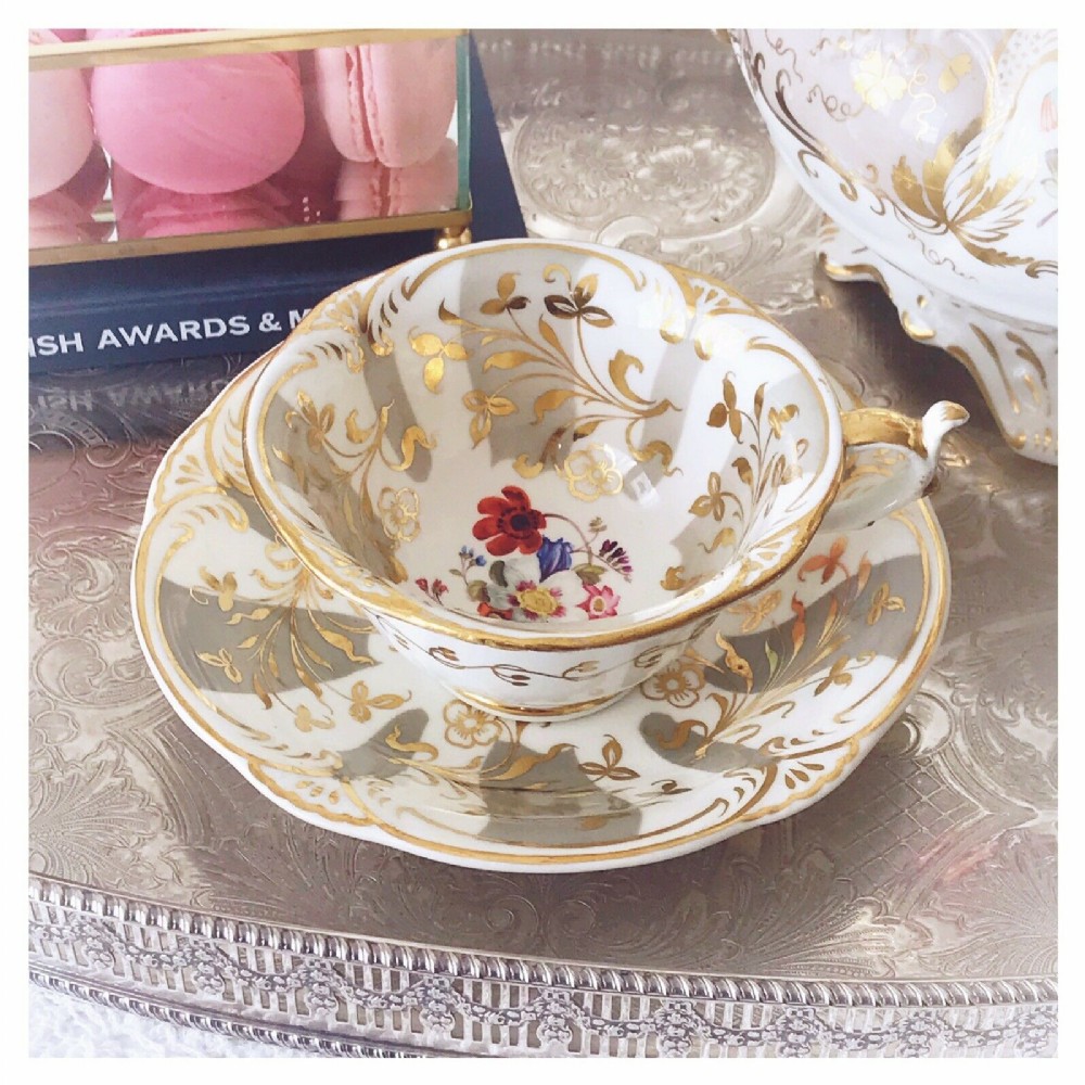 An antique Rockingham teacup and saucer set decorated with flowers and gilding