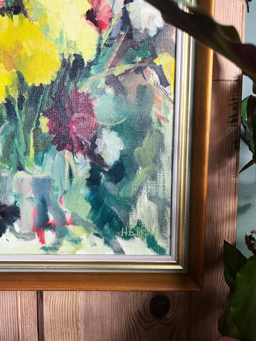 A framed mid-century oil on board painting featuring a colourful floral still life composition with yellow, pink, and green tones set within a wooden frame. View XI