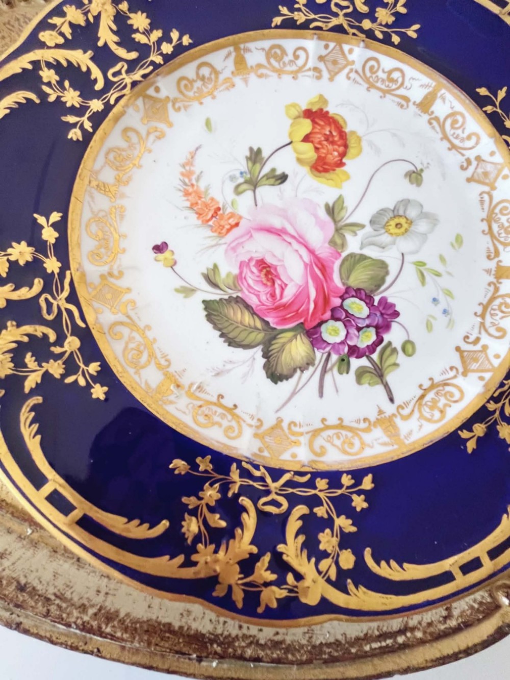 An antique Coalport porcelain dessert plate featuring a central hand-painted floral bouquet surrounded by a rich cobalt blue rim decorated with ornate gold gilding. View VI