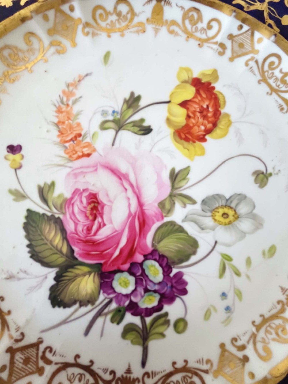 An antique Coalport porcelain dessert plate featuring a central hand-painted floral bouquet surrounded by a rich cobalt blue rim decorated with ornate gold gilding. View IX